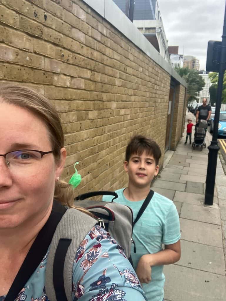 a family walking down the side of the road in london england at earl's court. a woman, a boy, a small boy, a man